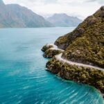 Nelson Car Rental vehicle driving along a scenic coastal highway in Nelson, New Zealand